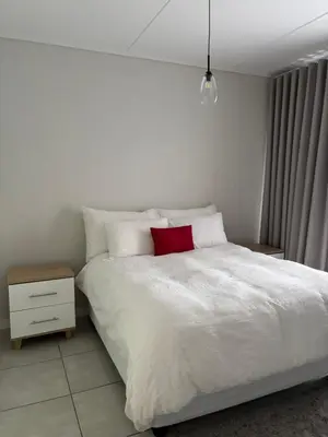 a bedroom with a white bed with a red pillow at The Dream Escape At The Blyde - Lagoon Facing 3 Bedroom Apartment in Pretoria