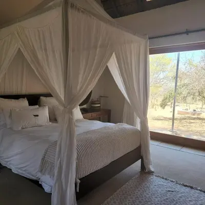 a bedroom with a canopy bed with a window at Mokaikai - Pride Retreat - Pax 10 in Bobbejaanstert