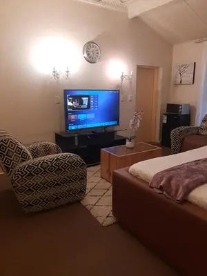 a living room with a flat screen tv and a bed at Portia inn accommodation in Pretoria