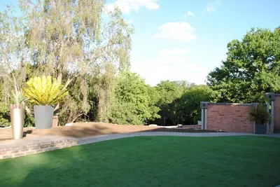 a yard with a green lawn and a brick wall at B and B Sandton in Johannesburg