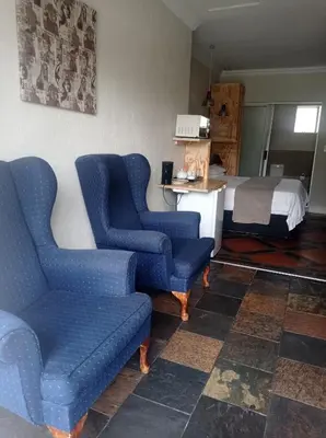 a room with two blue chairs and a bed at B and B Sandton in Johannesburg