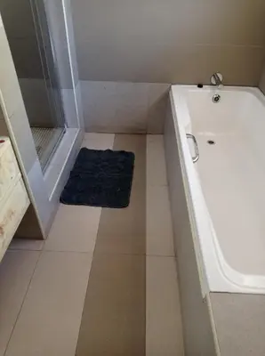 a small bathroom with a tub and a blue rug at B and B Sandton in Johannesburg
