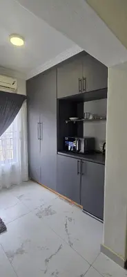 an empty kitchen with grey cabinets and a window at Good night guest house in Polokwane