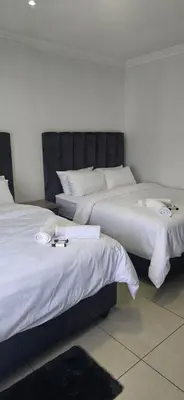two beds in a hotel room with white sheets at Good night guest house in Polokwane