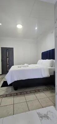 a bedroom with a large bed with white sheets at Good night guest house in Polokwane