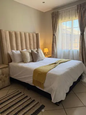 a bedroom with a large white bed with a window at Awesome family home in Midrand