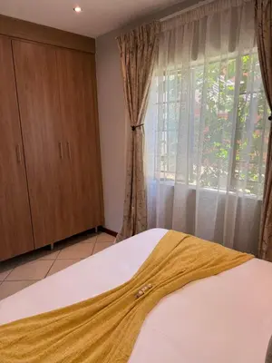 a bedroom with a bed and a window with curtains at Awesome family home in Midrand