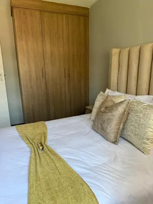 a bed with two pillows and a wooden cabinet at Awesome family home in Midrand