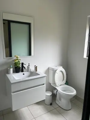 a white bathroom with a toilet and a sink at Lux Easy Stay in Pretoria