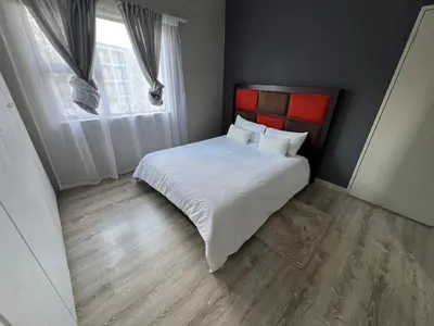a bedroom with a bed with white sheets and a window at Spacious Apartment Near Gautrain, Gallagher & MOA in Midrand