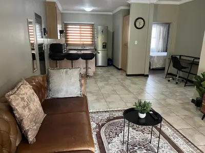 a living room with a couch and a kitchen at Spacious Apartment Near Gautrain, Gallagher & MOA in Midrand
