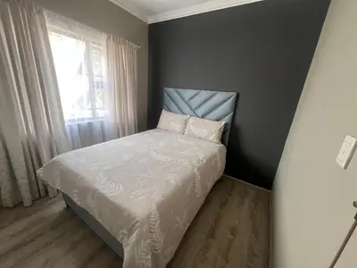 a small bedroom with a bed with white sheets and a window at Spacious Apartment Near Gautrain, Gallagher & MOA in Midrand