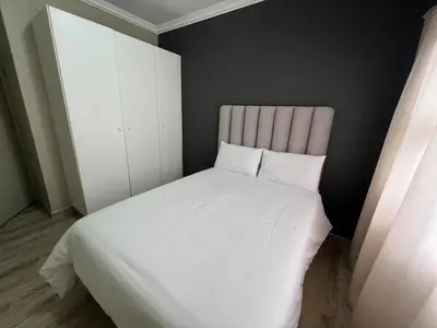 a bedroom with a white bed and a white cabinet at Spacious Apartment Near Gautrain, Gallagher & MOA in Midrand