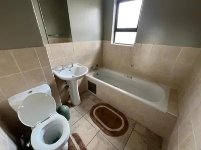 a bathroom with a toilet and a sink and a tub at Spacious Apartment Near Gautrain, Gallagher & MOA in Midrand