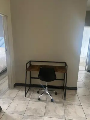 a desk with a black chair in a room at Spacious Apartment Near Gautrain, Gallagher & MOA in Midrand