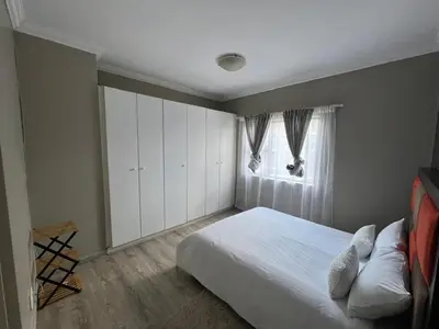 a bedroom with a white bed and a window at Spacious Apartment Near Gautrain, Gallagher & MOA in Midrand
