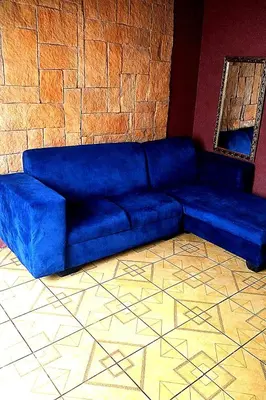 a blue couch in a room with a brick wall at Ndou The Rocks Lodge in Hammanskraal Station