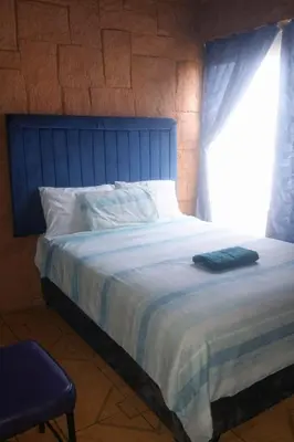 a bedroom with a large bed with a window at Ndou The Rocks Lodge in Hammanskraal Station