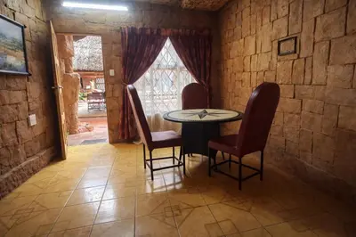 a table and chairs in a room with a window at Ndou The Rocks Lodge in Hammanskraal Station