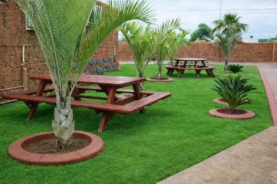 two picnic tables and a palm tree in the grass at Ndou The Rocks Lodge in Hammanskraal Station