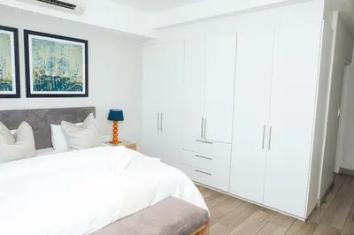 a white bedroom with a large bed and white cabinets at Regency Apartment Hotel Unit 311 in Pretoria
