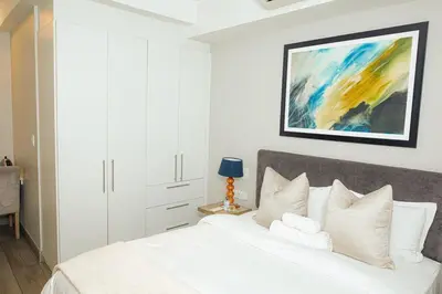 a bedroom with a white bed and a painting on the wall at Regency Apartment Hotel Unit 311 in Pretoria