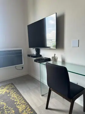 a room with a glass table with a chair and a television at Modern Studio Apartment in The Capital Trilogy in Pretoria