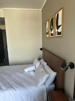 a bedroom with a bed with white sheets and pillows at Modern Studio Apartment in The Capital Trilogy in Pretoria