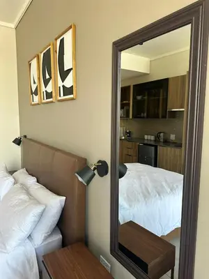 a mirror in a bedroom with a bed and a table at Modern Studio Apartment in The Capital Trilogy in Pretoria