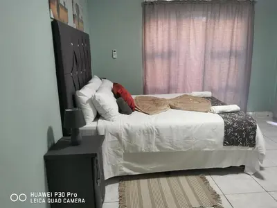 a bedroom with a bed with white sheets and pillows at A home away from Home in Musina