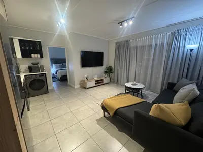 a living room with a couch and a tv at Diamond Suite Munyaka in Midrand