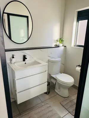 a bathroom with a white toilet and a mirror at Diamond Suite Munyaka in Midrand