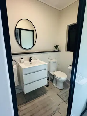 a bathroom with a sink and a toilet and a mirror at Diamond Suite Munyaka in Midrand