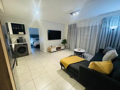 a living room with a couch and a tv at Diamond Suite Munyaka in Midrand