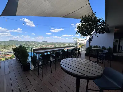 a deck with a table and chairs on a balcony at Signature Luxury Living Experience - The Trilogy Collection in Pretoria
