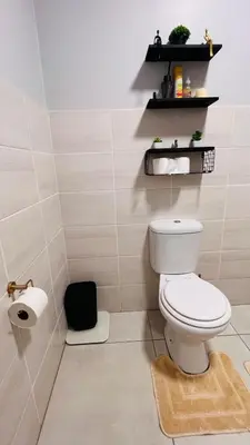 a bathroom with a toilet and a black shelf at UrbanCharm home away from home Affordable Luxury in Polokwane