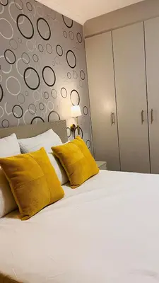 a bedroom with a white bed with yellow pillows at UrbanCharm home away from home Affordable Luxury in Polokwane