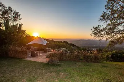 a sunset over a garden with a table and chairs at Panorama View Pool House Steiltes in Nelspruit