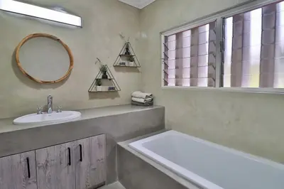 a bathroom with a tub and a sink and a mirror at Panorama View Pool House Steiltes in Nelspruit