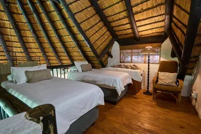 a bedroom with two beds and a lamp and a chair at Sable Ranch Selfsorg in Brits