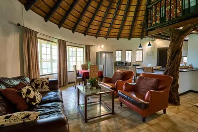 a living room with leather furniture and a kitchen at Sable Ranch Selfsorg in Brits