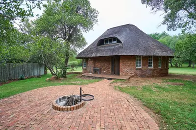 a small brick house with a thatched roof at Sable Ranch Selfsorg in Brits