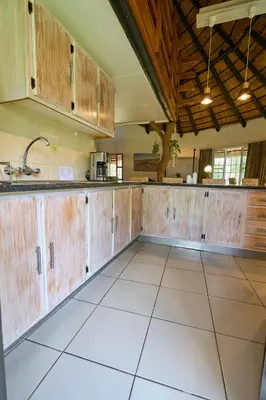 an empty kitchen with wooden cabinets and a tile floor at Sable Ranch Selfsorg in Brits