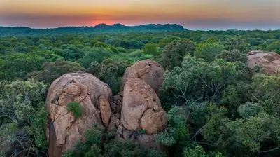 a group of large rocks in a forest at sunset at Sable Ranch Selfsorg in Brits