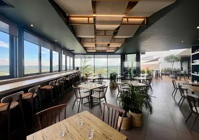 a restaurant with tables and chairs and windows at Deluxe fully furnished apartment in Menlyn Maine residence 902 in Pretoria