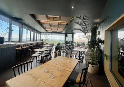 a restaurant with wooden tables and chairs and windows at Deluxe fully furnished apartment in Menlyn Maine residence 902 in Pretoria