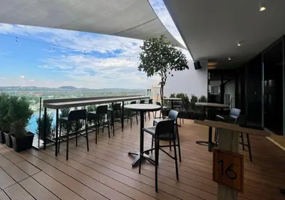 a balcony with tables and chairs on a building at Deluxe fully furnished apartment in Menlyn Maine residence 902 in Pretoria