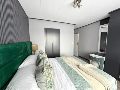a bedroom with a large bed with a green headboard at Legacy Suites Montana in Pretoria