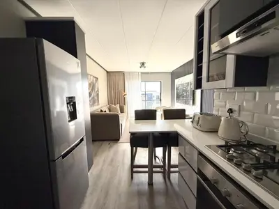 a kitchen with a refrigerator and a table with chairs at Legacy Suites Montana in Pretoria