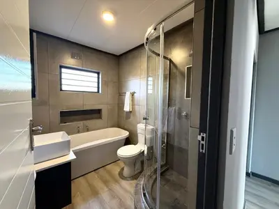 a bathroom with a toilet and a sink and a shower at Legacy Suites Montana in Pretoria
